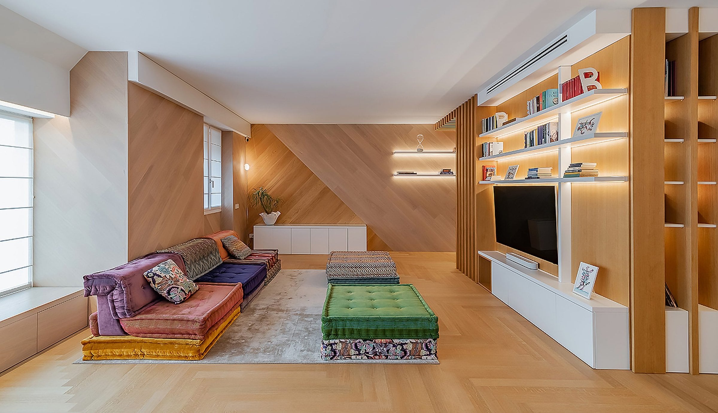 Soggiorno moderno ristrutturato con arredi su misura e finiture in legno, esempio di rinnovo degli spazi abitativi